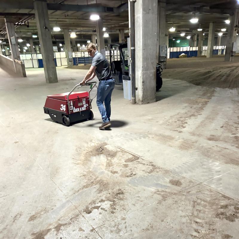 FactoryCat Walk Behind Floor Sweepers 34 backstage concrete - https://assets.factorycat.com/demoImages/2025/april/34-Walk Behind Floor Sweepers-backstage-concrete-Kansas City -USA-458.jpg - 800 - 800 - 458 A FactoryCat 34 walk behind battery floor sweeper cleaning the concrete floor at the rodeo in Kansas City, MO