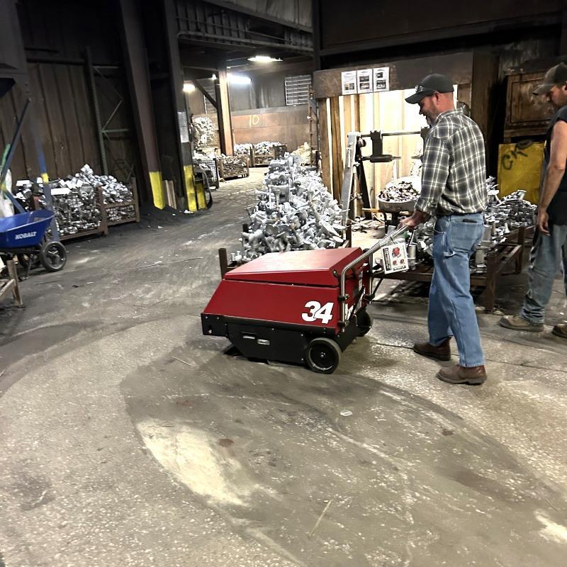 FactoryCat Walk Behind Floor Sweepers 34 production areas concrete - https://assets.factorycat.com/demoImages/2025/april/34-Walk Behind Floor Sweepers-production areas-concrete-St. Louis-USA-408.jpg - 800 - 800 - 408 A FactoryCat 34 battery floor sweeper cleaning the concrete maintenance shop floor of a foundry in St. Louis, MO