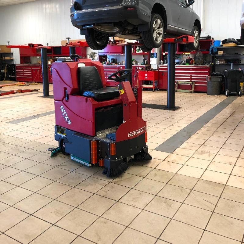 FactoryCat Ride On Floor Scrubbers GTX service bay tile floors - https://assets.factorycat.com/demoImages/2025/april/GTX-Ride On Floor Scrubbers-service bay-tile floors-Baltimore-USA-813.jpg - 800 - 800 - 813 GA FactoryCat GTX Ride On Floor Scrubber cleaning the tile floor of the service bay at a Baltimore, Maryland auto dealer