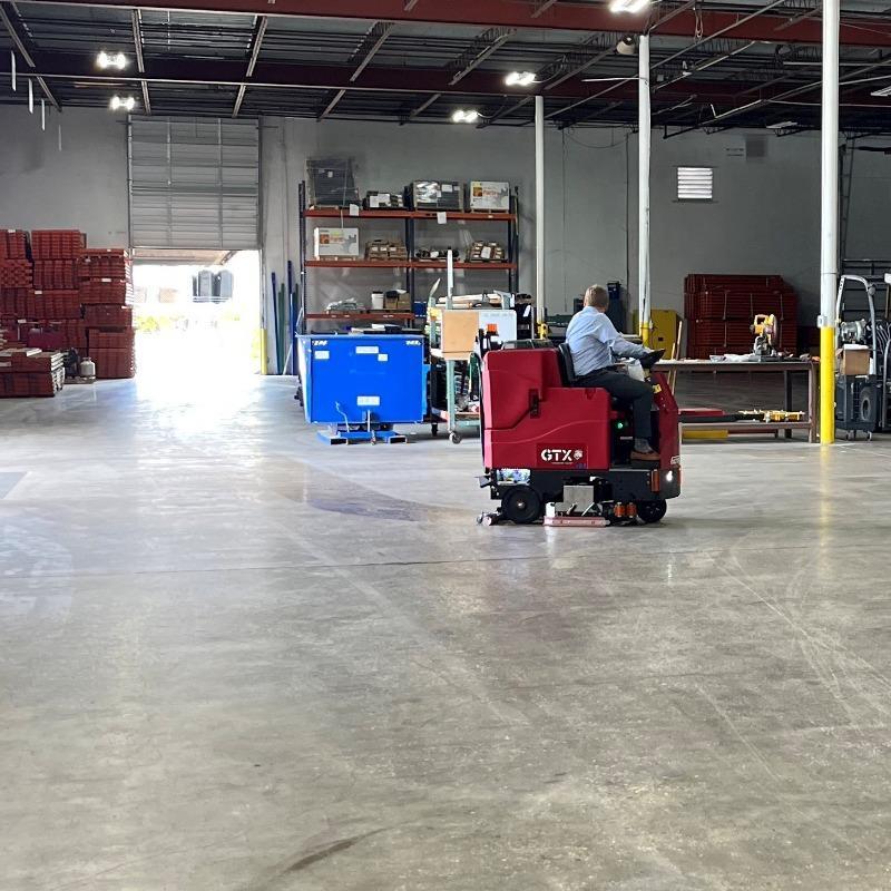FactoryCat Ride On Floor Scrubbers GTX warehouse concrete - https://assets.factorycat.com/demoImages/2025/april/GTX-Ride On Floor Scrubbers-warehouse-concrete-Wilmington-USA-931.jpg - 800 - 800 - 931 A FactoryCat GTX ride on floor scrubber cleaning the concrete warehouse floor in a Wilmington, North Carolina CNC shop