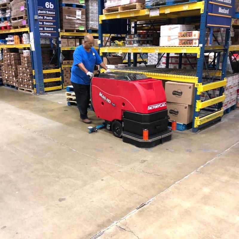 FactoryCat Walk Behind Floor Scrubbers Mag-HD aisles concrete - https://assets.factorycat.com/demoImages/2025/april/Mag-HD-Walk Behind Floor Scrubbers-aisles-concrete-Dallas -USA-806.jpg - 800 - 800 - 806 A FactoryCat Mag-HD Walk Behind Floor Scrubber is cleaning the concrete aisles of a Dallas, Texas warehouse club