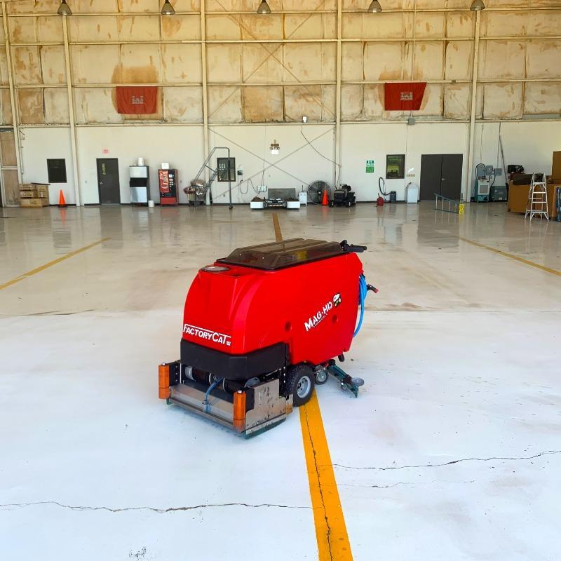 FactoryCat Walk Behind Floor Scrubbers Mag-HD hangar epoxy - https://assets.factorycat.com/demoImages/2025/april/Mag-HD-Walk Behind Floor Scrubbers-hangar-epoxy-Houston-USA-799.jpg - 800 - 800 - 799 A FactoryCat Mag-HD Walk Behind Floor Scrubber cleaning the epoxy floor in the hanger of a Houston, Texas FBO