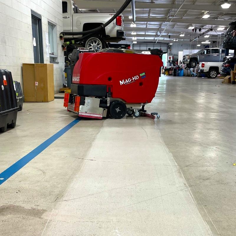 FactoryCat Walk Behind Floor Scrubbers Mag-HD shop concrete - https://assets.factorycat.com/demoImages/2025/april/Mag-HD-Walk Behind Floor Scrubbers-shop-concrete-Dallas-USA-320.jpg - 800 - 800 - 320 A FactoryCat Mag-HD Floor Scrubber cleaning the epoxy coated concrete floor at an auto dealer in Dallas Texas.