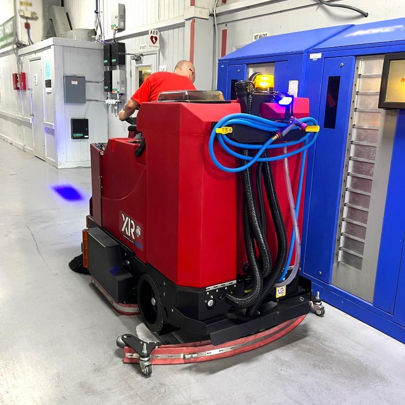 FactoryCat Ride On Floor Scrubbers XR production areas epoxy - https://assets.factorycat.com/demoImages/2025/april/XR-Ride On Floor Scrubbers-production areas-epoxy-Norcross-USA-449.jpg - 800 - 800 - 449 A FactoryCat XR battery rider floor scrubber cleaning epoxy in the aisles of a manufacturing facility in Norcross, GA