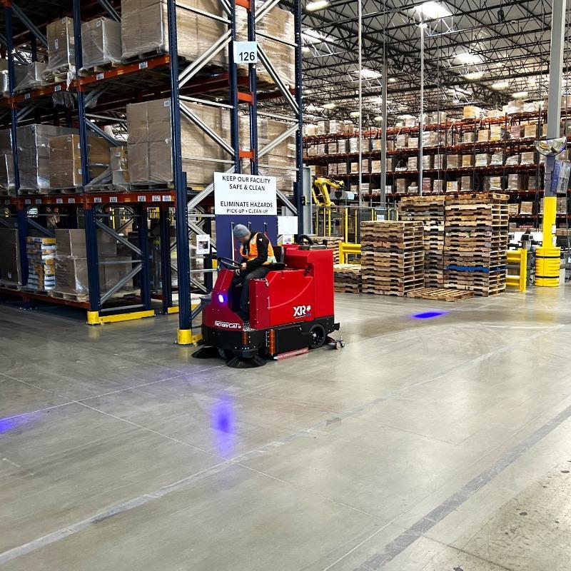 FactoryCat Ride On Floor Scrubbers XR warehouse concrete - https://assets.factorycat.com/demoImages/2025/april/XR-Ride On Floor Scrubbers-warehouse-concrete-Cleveland-USA-426.jpg - 800 - 800 - 426 A FactoryCat XR ride on battery floor scrubber cleaning the concrete floor of a distribution center in Cleveland, OH