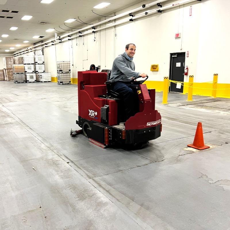 FactoryCat Ride On Floor Scrubbers XR warehouse concrete - https://assets.factorycat.com/demoImages/2025/april/XR-Ride On Floor Scrubbers-warehouse-concrete-Columbus-USA-429.jpg - 800 - 800 - 429 A FactoryCat XR ride on battery floor scrubber cleaning the epoxy floor of a chemical manufacturer in Cleveland, OH