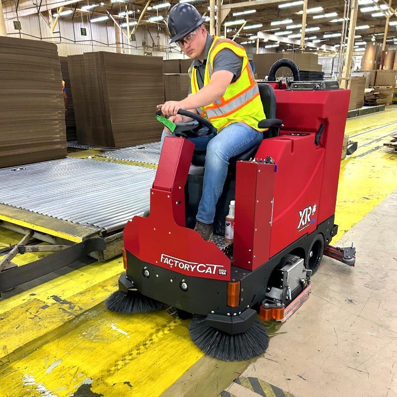 FactoryCat Ride On Floor Scrubbers XR warehouse epoxy - https://assets.factorycat.com/demoImages/2025/april/XR-Ride On Floor Scrubbers-warehouse-epoxy-Houston-USA-362.jpg - 800 - 800 - 362 A FactoryCat XR ride on floor scrubber cleaning the epoxy floor in a warehouse at a cardboard converter in Houston, TX.